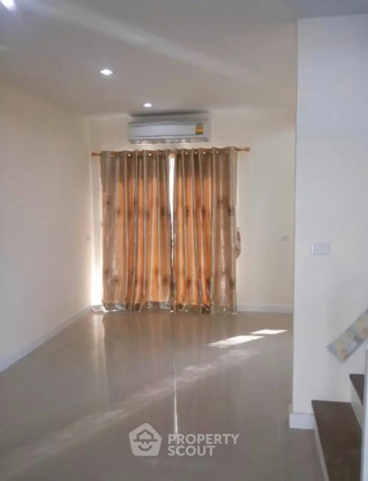 Spacious living room with air conditioning and elegant curtains, perfect for modern living.