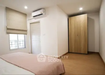 Cozy bedroom with modern air conditioning and ample natural light, featuring a sleek wardrobe and minimalist design.