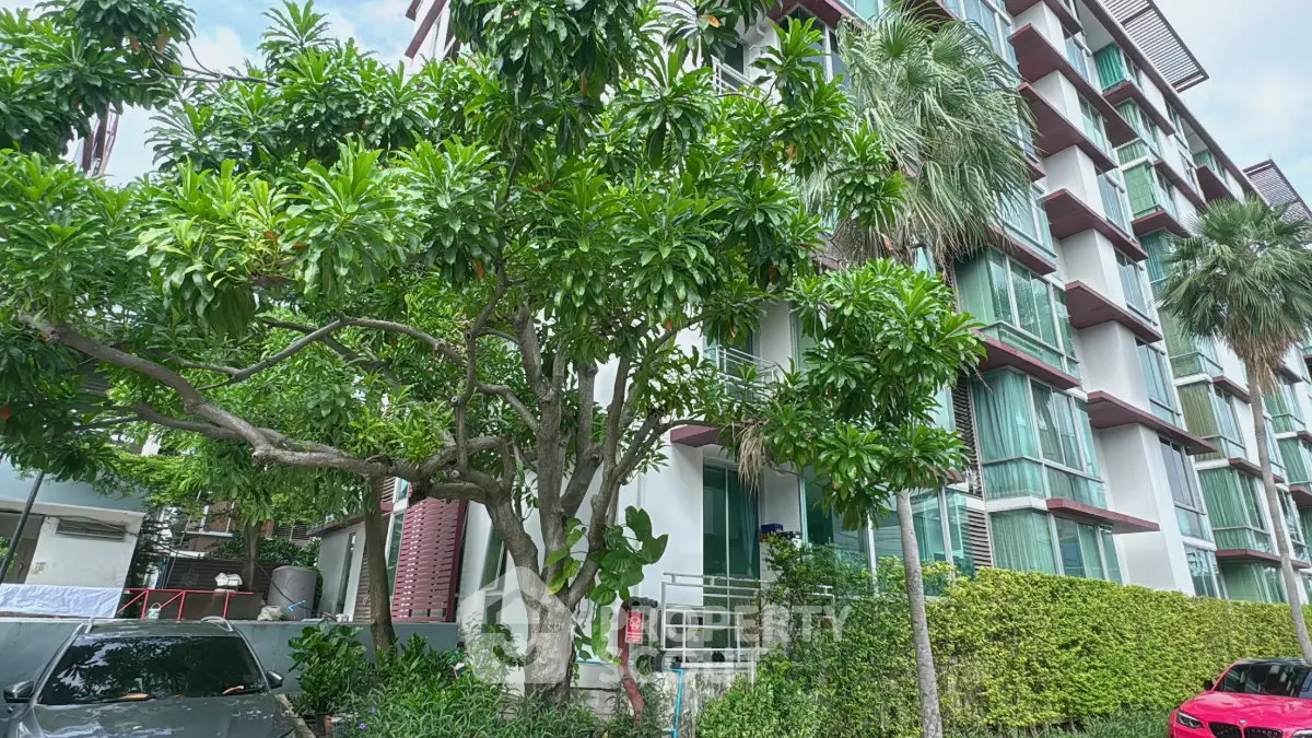 Modern residential building with lush greenery and large windows, showcasing urban living with natural surroundings.