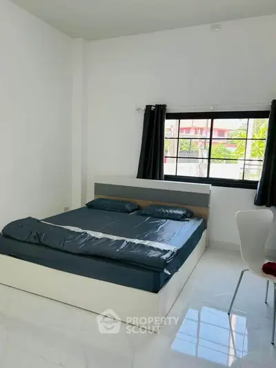 Modern bedroom with sleek design and large window offering natural light.
