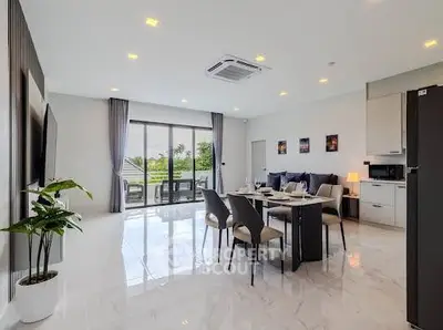 Spacious modern living room with dining area and large windows offering natural light and garden view.
