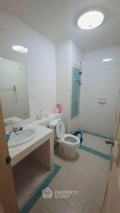 Spacious bathroom with modern fixtures and ample lighting, featuring a shower and vanity area.