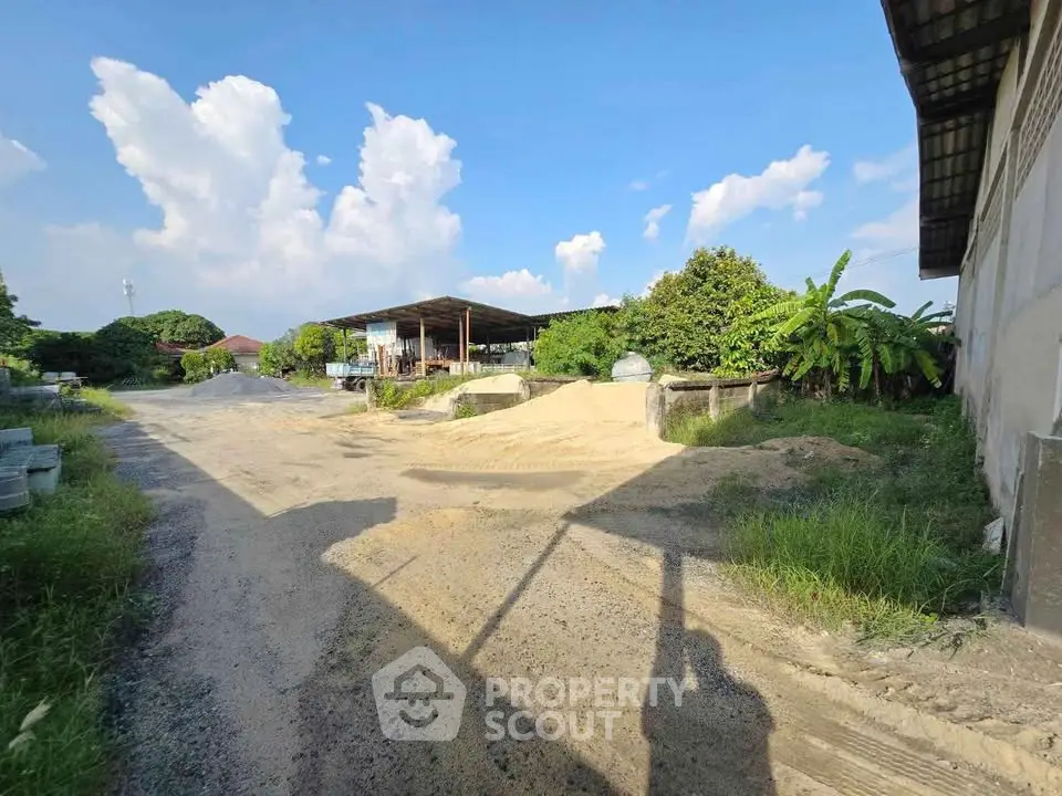 Expansive industrial property with open storage space and lush greenery, ideal for development opportunities.