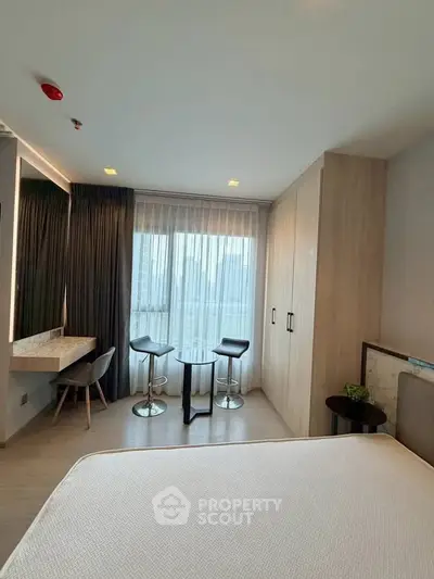 Modern bedroom with city view, featuring stylish furniture and natural light.