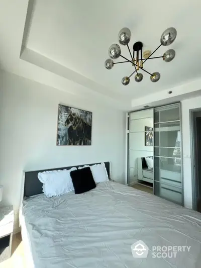 Modern bedroom with stylish chandelier and sliding wardrobe doors