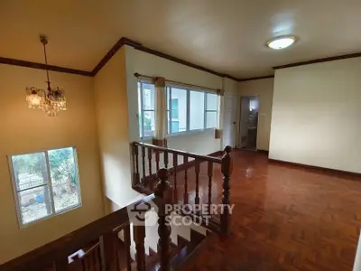 Spacious upper-level hallway with wooden flooring and large windows