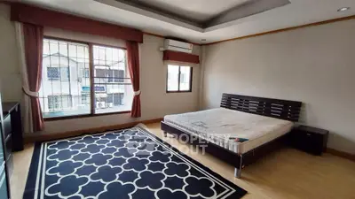 Spacious bedroom with large window and modern decor in a well-lit apartment.