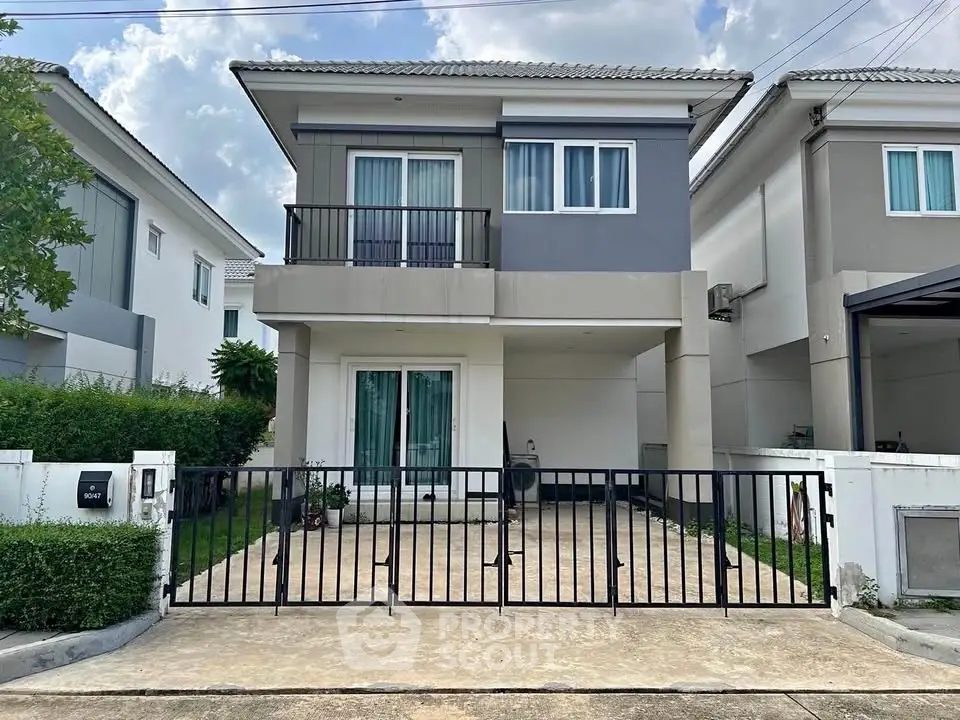 Modern two-story house with gated driveway and stylish facade in a suburban neighborhood.
