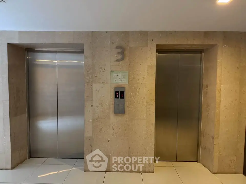 Modern building elevator lobby with two stainless steel elevators on the third floor.