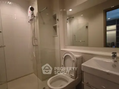 Modern bathroom with glass shower and sleek fixtures in contemporary apartment.