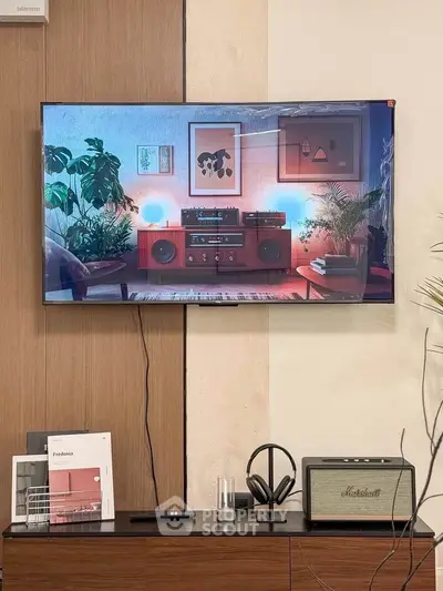 Stylish living room with modern decor, featuring a mounted TV, sound system, and lush indoor plants.