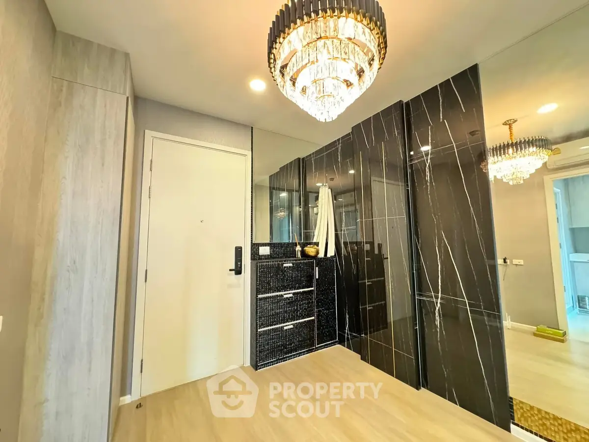 Luxurious modern entryway with elegant chandelier and sleek black marble accents