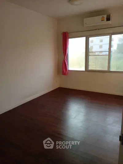 Spacious empty room with hardwood floors and large window