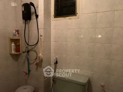 Cozy bathroom with tiled walls and essential fixtures, featuring a shower and toilet.