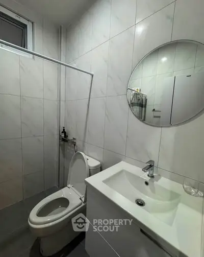 Modern bathroom with sleek white fixtures and round mirror in a stylish real estate property.