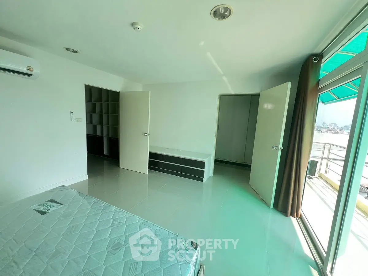 Spacious bedroom with balcony access and ample natural light in modern apartment.