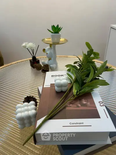 Stylish interior decor with books and plants on a modern glass table, perfect for a cozy living room.