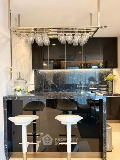 Luxurious modern kitchen with sleek black marble countertops and stylish bar stools.