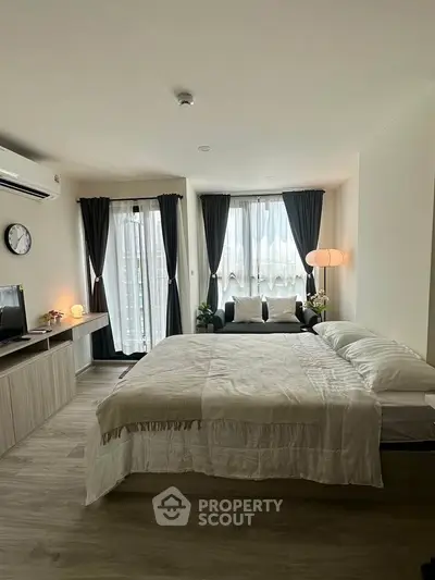 Modern bedroom with cozy decor and natural light, featuring a stylish bed and elegant curtains.