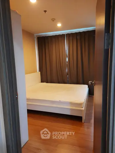 Cozy bedroom with wooden flooring and large window curtains