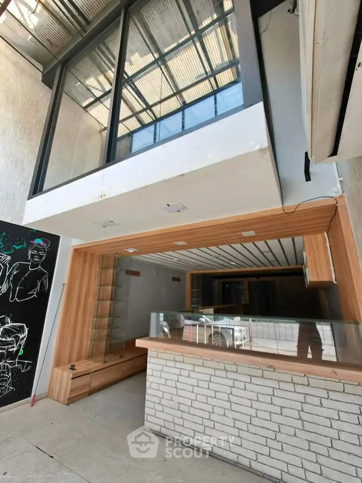 Modern commercial space with stylish wood and brick interior, featuring large windows and sleek design.