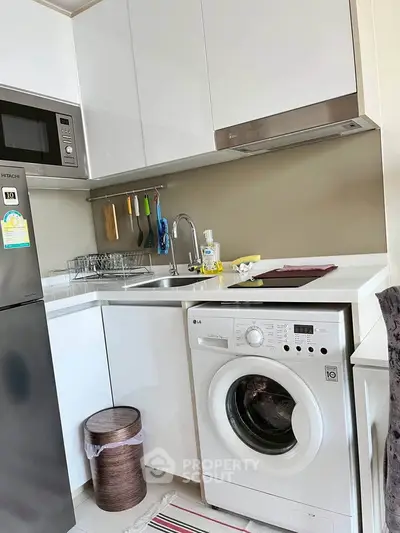 Modern kitchen with sleek white cabinets, built-in appliances, and washing machine in compact layout.