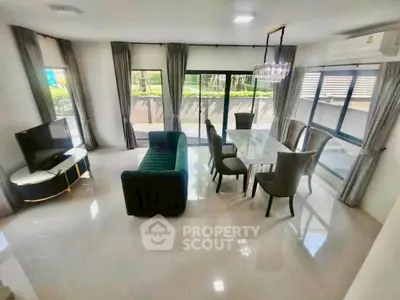 Spacious living room with modern furniture and large windows offering garden views.