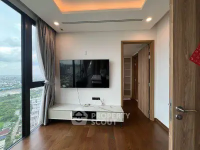 Modern living room with large window and city view, featuring a wall-mounted TV and sleek wooden flooring.