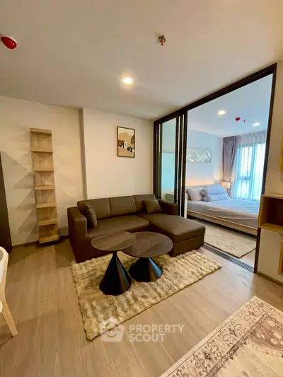 Modern living room with cozy sofa and stylish decor adjacent to a serene bedroom.