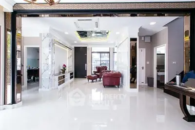 Luxurious open living room with marble accents and elegant red leather seating.