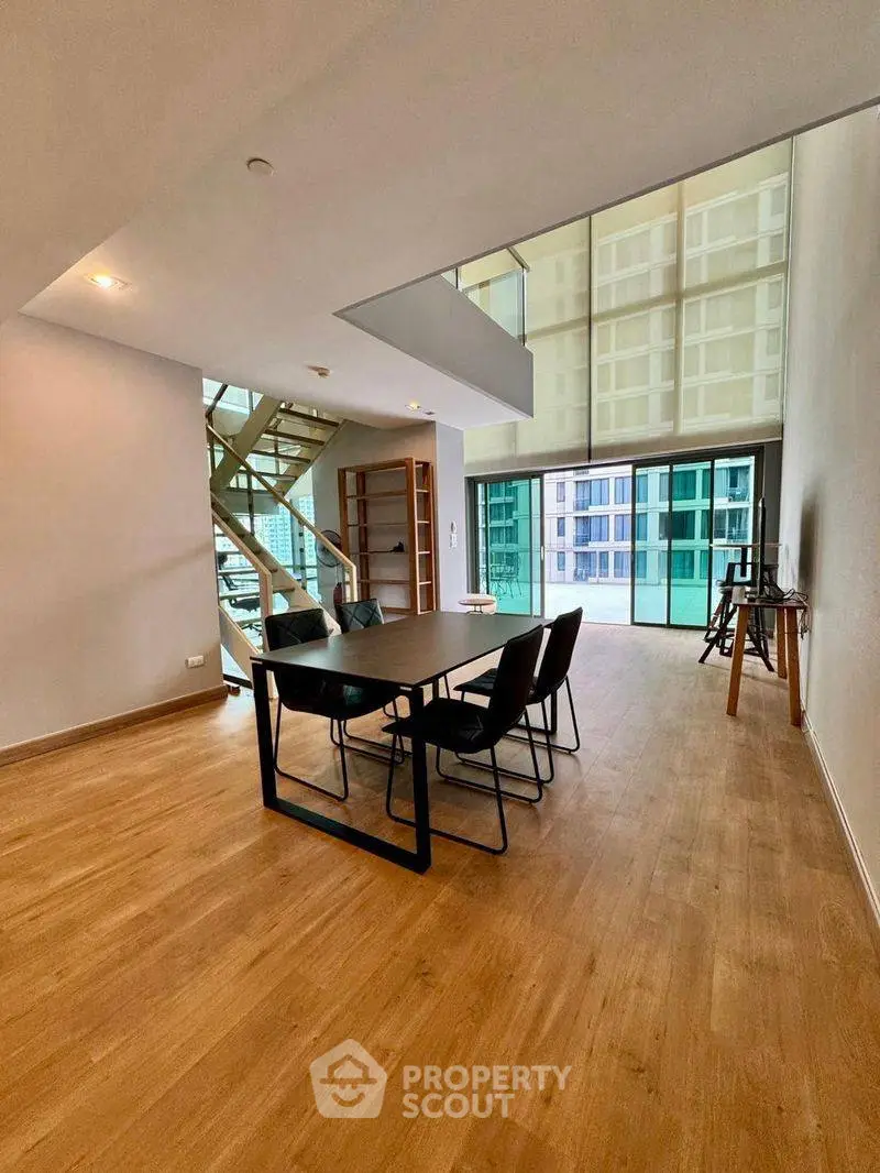 Spacious modern living room with high ceilings and large windows offering city views.