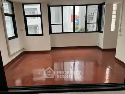 Spacious corner unit with large windows and polished wooden floors in a modern apartment.