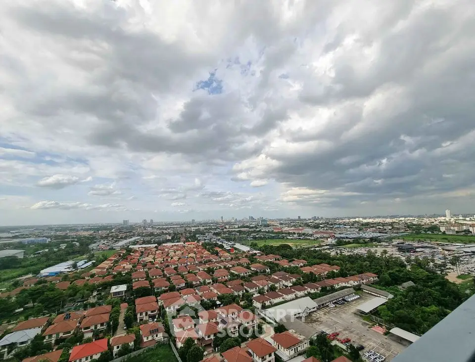 Stunning aerial view of suburban neighborhood with red-roofed houses under dramatic cloudy sky.