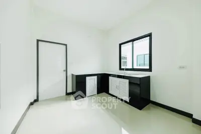 Minimalist kitchen with sleek black cabinets and large window