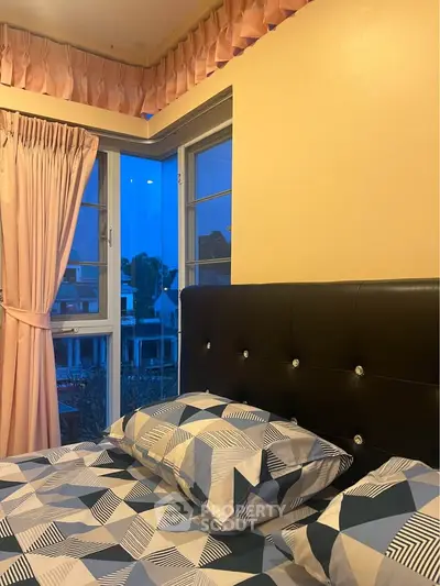 Cozy bedroom with stylish bed and large windows offering a serene evening view.