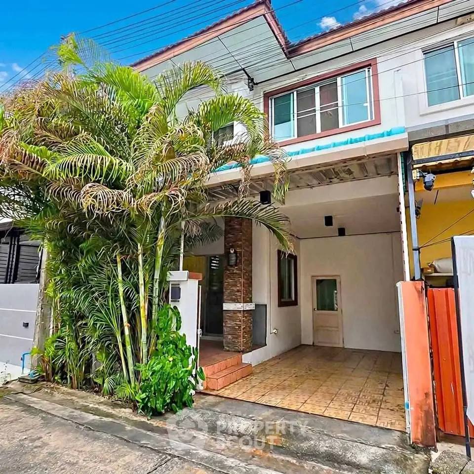 Charming townhouse with lush greenery and spacious driveway in a serene neighborhood.