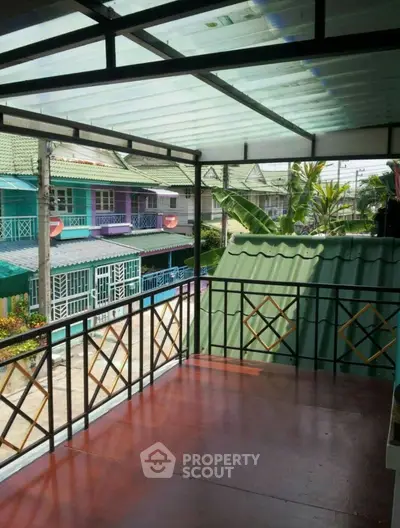 Charming balcony with decorative railing and roof, overlooking colorful neighborhood houses.
