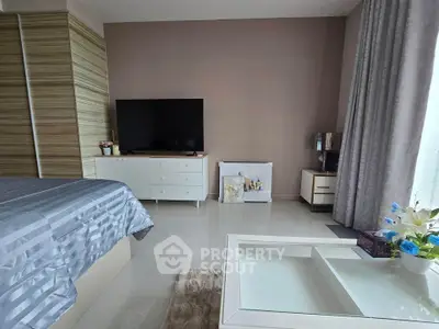 Modern bedroom with sleek decor, featuring a large TV, stylish furniture, and elegant curtains for a cozy ambiance.