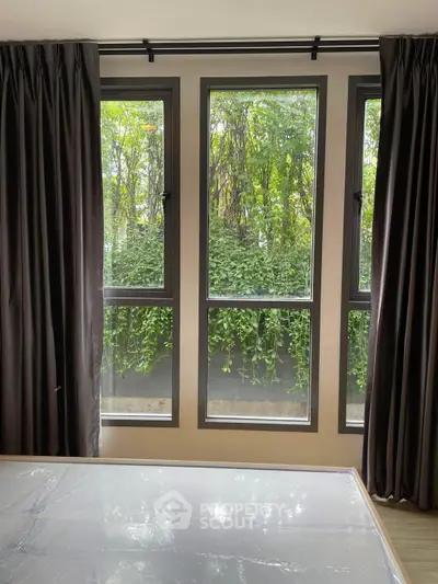 Bright bedroom with large windows and lush greenery view