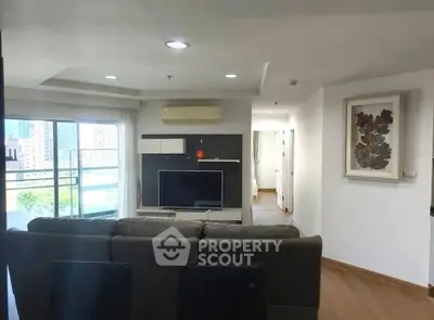 Spacious modern living room with large windows and city view, featuring sleek furniture and stylish decor.