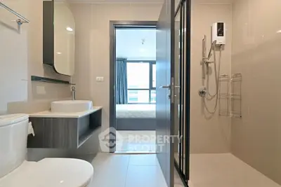Modern bathroom with sleek fixtures and view into a bright bedroom