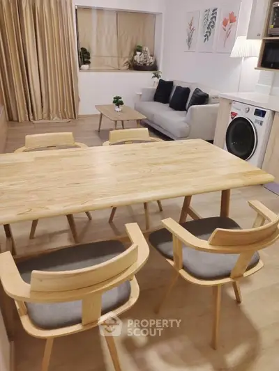 Modern dining area with wooden table and chairs, cozy living room with sofa and washing machine.