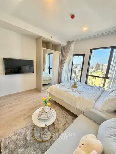 Modern bedroom with city view, cozy seating, and stylish decor