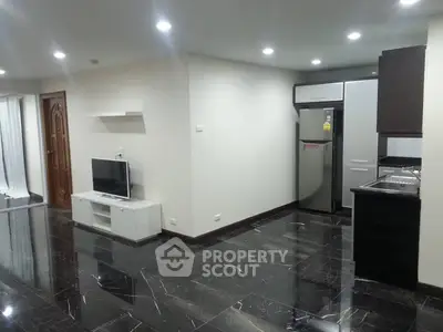 Modern open-plan living room with sleek black marble flooring and stylish kitchen area.