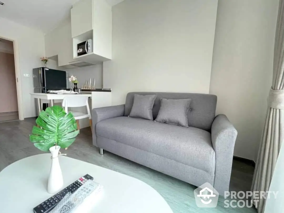 Modern minimalist living room with a comfortable grey sofa, sleek white coffee table, and a vibrant green plant adding a touch of nature.