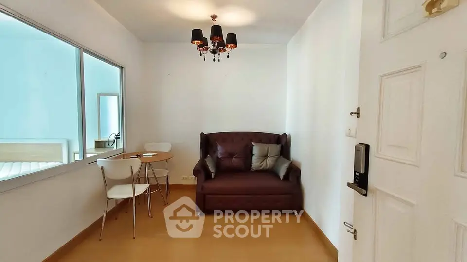 Cozy living room with elegant chandelier and compact dining area in modern apartment.