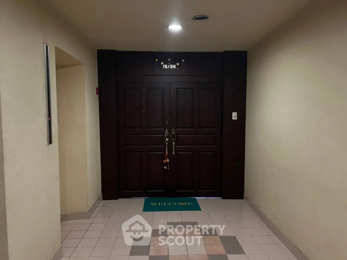 Elegant apartment entrance with dark wood double doors and welcome mat