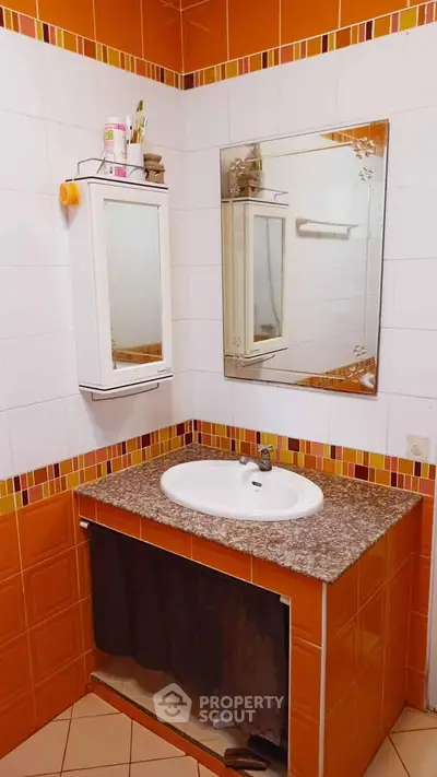 Charming bathroom with stylish orange tiles and modern vanity mirror