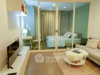 Modern studio apartment with cozy living area and stylish bedroom separated by glass doors.