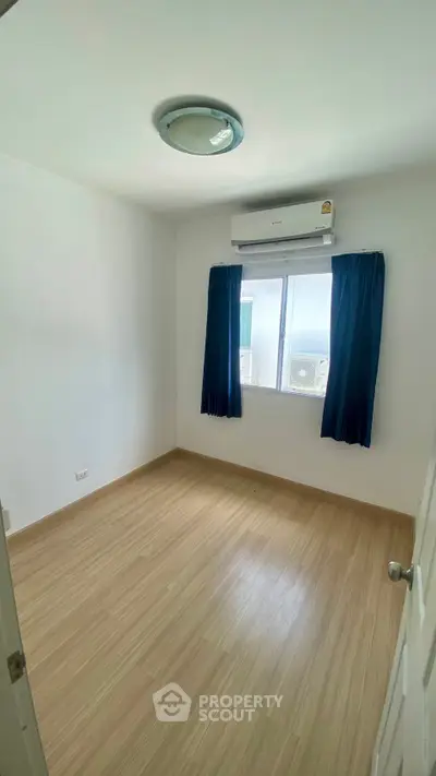 Spacious empty room with wooden flooring and air conditioning, perfect for customization.
